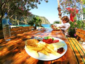 厄吕代尼兹Butterfly Valley Beach Glamping with Food的坐在餐桌上吃一盘食物的孩子