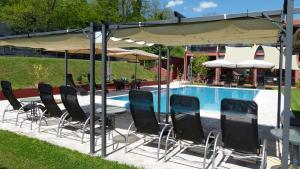 萨尔扎纳阿尔伯格拉鲁纳酒店的一组桌椅,放在泳池边的伞下
