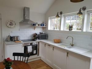 布里斯托The Cottage的厨房配有白色橱柜、水槽和窗户。