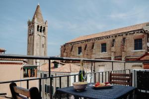 威尼斯Palazzetto Barnaba的一个带钟楼的阳台的桌子和一碗水果