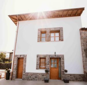 BalmoriEl Riveru - Astur Casas Rurales的白色的房子,设有棕色的门和窗户
