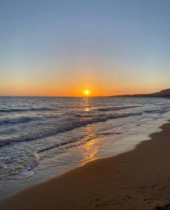 里贝拉Accogliente Appartamento Costa Makauda的日落在海滩上与大海