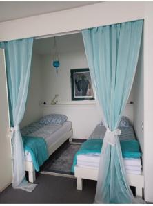 阿斯科纳Sollevante Ascona的卧室内的两张床,配有蓝色窗帘
