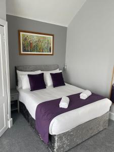 德里门Elmbank Stay - Drymen的一间卧室配有一张大床,提供紫色和白色枕头