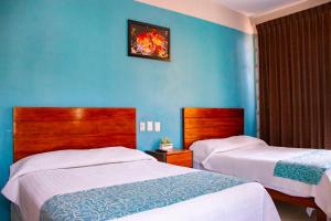 阿卡普尔科Acapulco Amor的一间卧室设有两张床和蓝色的墙壁