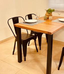 Villa HipódromoCOMPLEJO ZAPALA的一张木桌,配有两把椅子和两杯葡萄酒