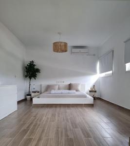 阿比让La Maison de Kouadio的一间铺有木地板的白色卧室,配有一张床
