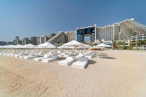 迪拜FIVE Palm Resort - Luxury 2BR - Sea View的海滩上一排白色的椅子和遮阳伞