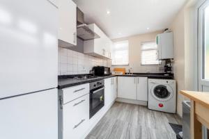 依尔福Highlands Gardens Suites的厨房配有白色橱柜、洗衣机和烘干机