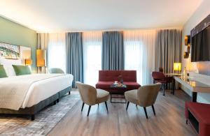 奥格斯堡Leonardo Hotel Augsburg的酒店客房设有一张大床和一张书桌。