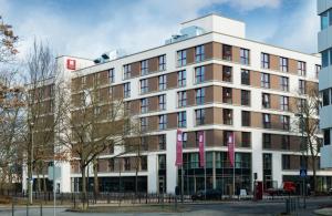 奥芬巴赫Leonardo Hotel Offenbach Frankfurt的一座白色的大建筑,上面有粉红色的横幅