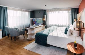克洛滕Leonardo Hotel Zurich Airport的一间卧室配有一张床和一张书桌及电视