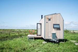 卡罗利嫩西尔Tiny House Pioneer 18 Zur Meerseite - Green Tiny Village Harlesiel的坐在草地上的一个小房子