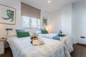 加的斯Brisas Playa 3 Baños的配有绿色枕头和书籍的客房内的两张床