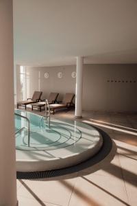 黑灵斯多夫欧斯特布里克塔德酒店的一个带椅子的房间,有一个大型玻璃热水浴缸