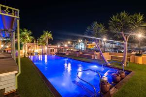 阿尔布费拉Vila Origens Boutique Hotel Albufeira – Adults Only的棕榈树和灯光的夜间游泳池