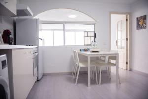 洛斯雷亚莱霍斯SUNSET HOME wifi的厨房配有白色的桌椅和窗户。