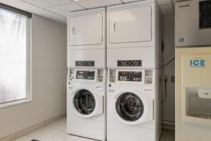 退休小镇村庄智选假日酒店的洗衣房配有3台洗衣机和烘干机