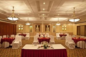 古尔冈布里斯托尔酒店的宴会厅配有桌子、白色椅子和灯