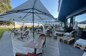 Saint Aubin SaugesHôtel Restaurant Port-Conty的一个带桌椅和遮阳伞的户外庭院。