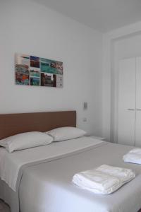 加利波利La Scogliera的两张带白色床单的床和一张墙上的照片