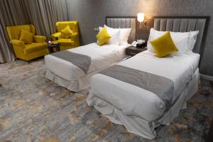 泰布克فندق دبليو اس ws的两张位于酒店客房的床,配有黄色椅子