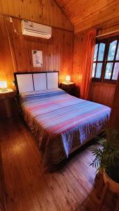 科隆Cabañas Pulmahue的木制客房内的一间卧室,配有一张床