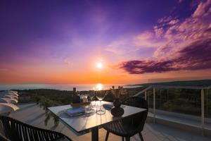 诺瓦利娅Hotel In Excelsis的阳台的桌椅享有日落美景