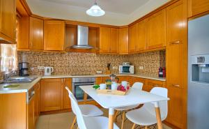 卡西奥皮Villa Spiros Imerolia Kassiopi的厨房配有木制橱柜和白色的桌椅