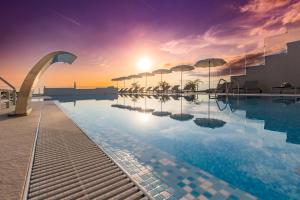 诺瓦利娅Hotel In Excelsis的一座享有日落美景的建筑屋顶上的游泳池