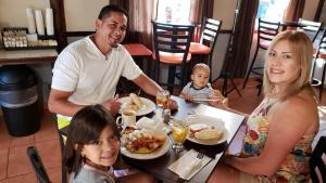 卡沃罗霍Combate Beach Resort的坐在餐桌旁吃饭的家庭