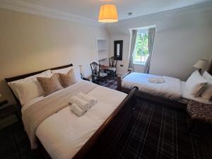 福特罗斯Clematis Cottage, Fortrose的一间卧室设有两张带白色床单的床和窗户。