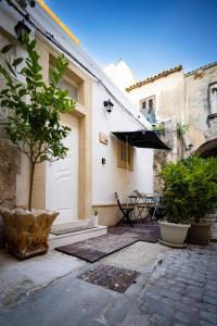 锡拉库扎La Casetta del Ronco1 Ortigia的庭院设有白色门、桌子和遮阳伞。