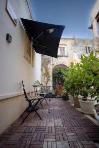 锡拉库扎La Casetta del Ronco1 Ortigia的庭院配有桌子和黑伞。