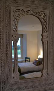 彭林无花果树屋住宿加早餐旅馆的卧室内的镜子反射着一张床