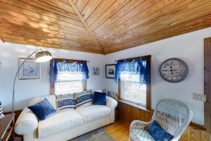 圣奥古斯丁Crescent Beach Cottage的客厅配有沙发和墙上的时钟