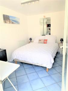 勒布斯卡Chambre cosy indépendante dans jardin verdoyant.的卧室配有白色的床和蓝色的瓷砖地板。