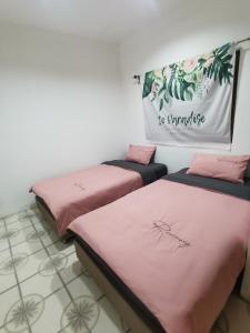 乌隆他尼Aim Houze的配有粉红色床单的客房内的两张床