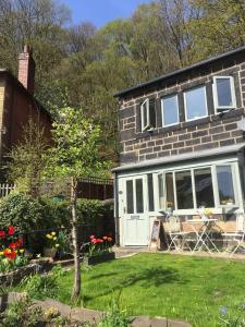 海伯敦桥Calderside Cottage (2 BDR Central Hebden Bridge)的砖屋,有白色的门和院子