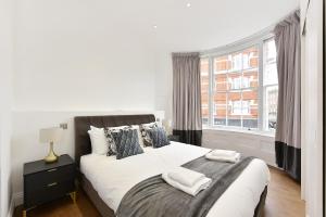 伦敦London Choice Apartments - Chelsea - Sloane Square的一间卧室配有一张床,上面有两条毛巾