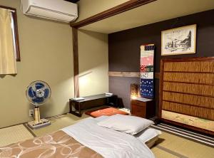 奈良奈良町宾馆的一间卧室配有一张床、一张桌子和风扇