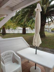 安格雷Petit oasis avec piscine的白色桌子和白色遮阳伞及长凳