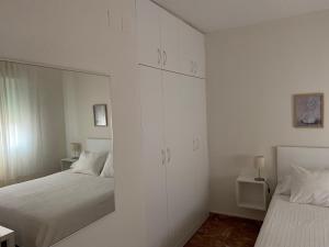 埃希哈APARTAMENTO PLAZA ESPAÑA的一间白色卧室,配有两张床和镜子