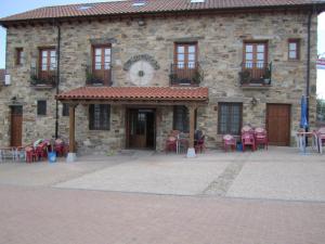 Santa Colomba de SomozaHotel Rural El Molinero de Santa Colomba de Somoza的前面设有桌椅的建筑