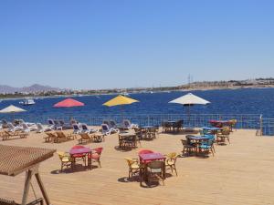 沙姆沙伊赫Jewel Sharm El Sheikh Hotel的水面上带桌椅和遮阳伞的甲板