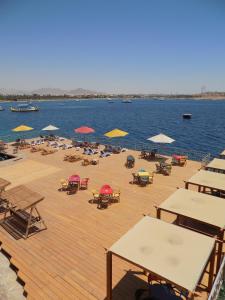 沙姆沙伊赫Jewel Sharm El Sheikh Hotel的水面上带椅子和遮阳伞的木制甲板