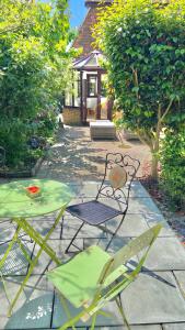 贝克斯希尔Beautiful Bexhill Cottage with garden 3 mins walk to beach的庭院设有两把椅子和一张桌子,还有一间房子