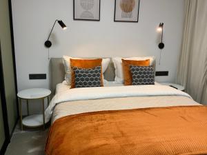 德鲁斯基宁凯Alėjos Apartmentai City的一间卧室配有一张带橙色毯子和枕头的床