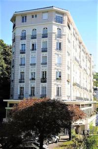 艾克斯莱班Grand studio 38m2 dans ancien palace avec piscine et place de parking privée的一座高大的白色建筑,前面有一棵树