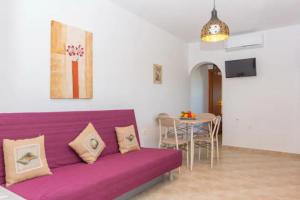 纳克索乔拉Villa Galante, (croft house nearby the sea)的客厅配有一张紫色沙发,配有一张桌子